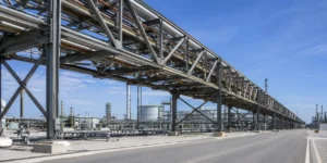 Corredor de estanterías de tubos de acero industriales de largo alcance que soporta múltiples tuberías de proceso en una planta