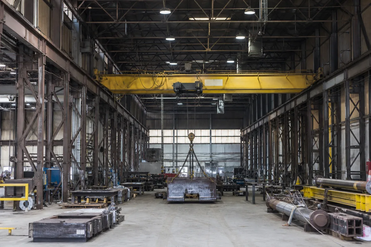 Overhead bridge crane applying operational loads to steel workshop columns and runway beams